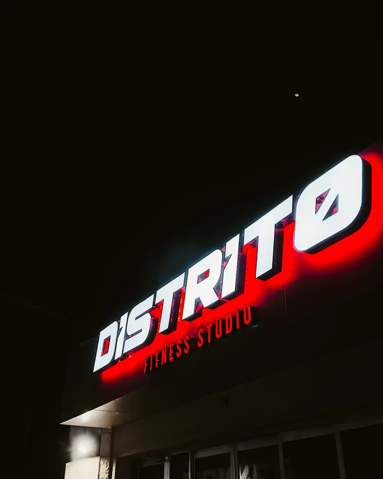 Fachada de Distrito en L. Montejano con el letrero encendido de noche